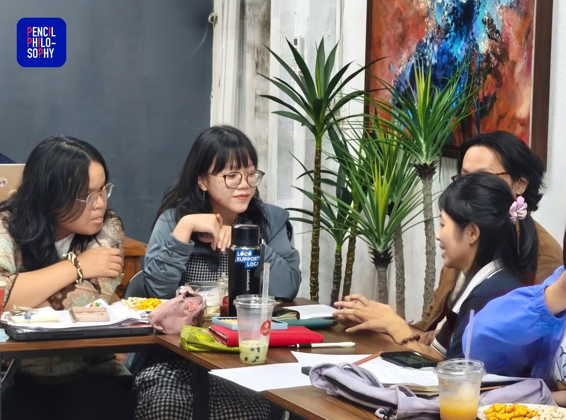Học viên thảo luận quanh bàn với tài liệu và đồ uống