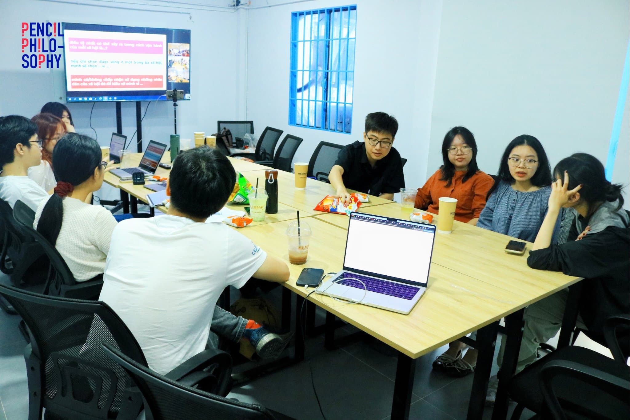 Toàn cảnh phòng seminar, hội viên ngồi quanh bàn trước màn hình chiếu slide